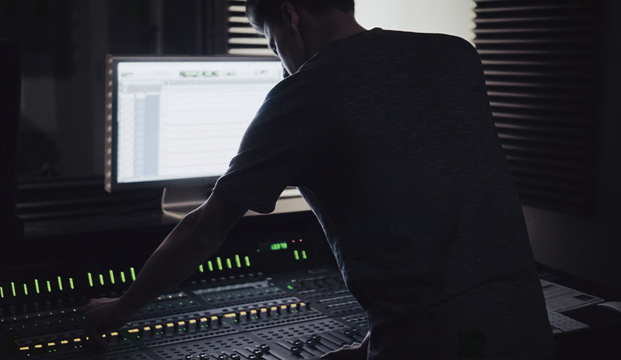 man edits audio on a workstation