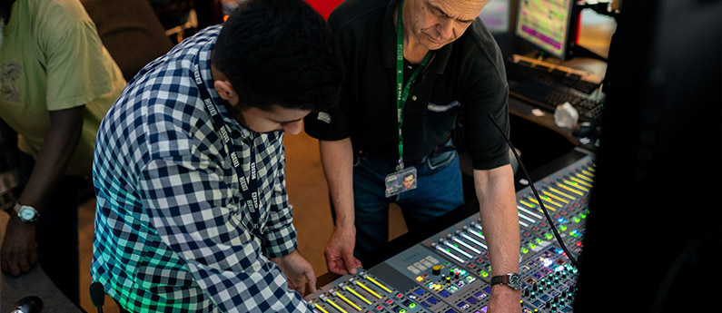 Instructor shows student options on an audio video production workstation