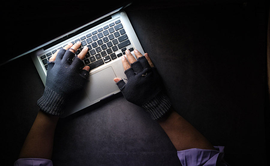 Someone types on a laptop using frayed fingerless gloves