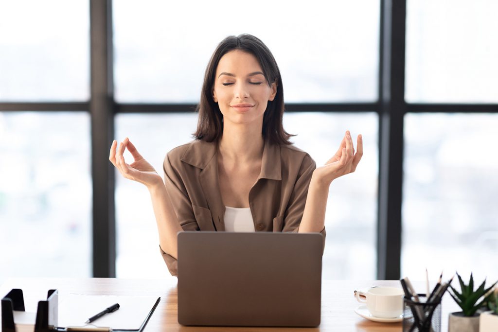 Woman with arms raised in front of a laptop